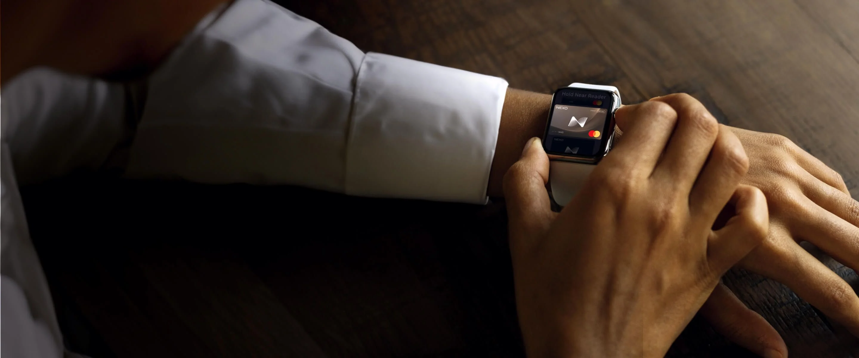 A man wearing a smartwatch on his left wrist activates a virtual card on the device's screen, using his other hand to interact with the display.